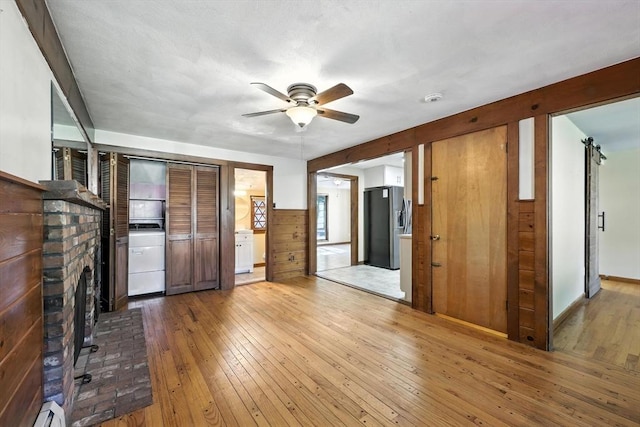 51 Glenview Dr, West Springfield, MA 01089 - unfurnished living room featuring hardwood / wood-style floors, a ceiling fan, a fireplace, baseboard heating, and washer / dryer