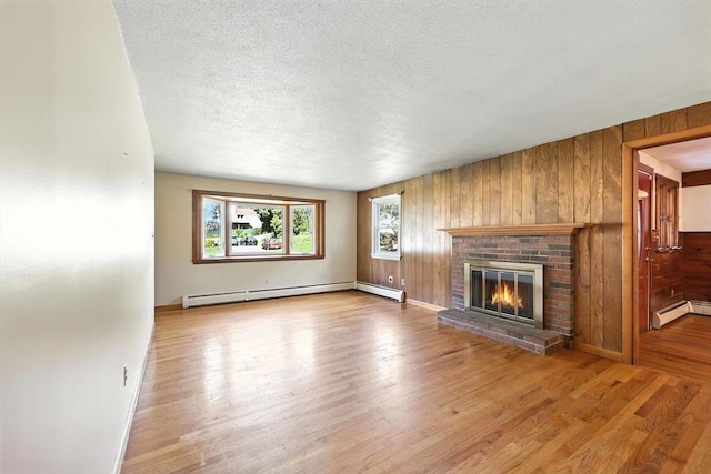 51 Glenview Dr, West Springfield, MA 01089 - unfurnished living room featuring baseboard heating, wooden walls, a fireplace, wood finished floors, and a textured ceiling