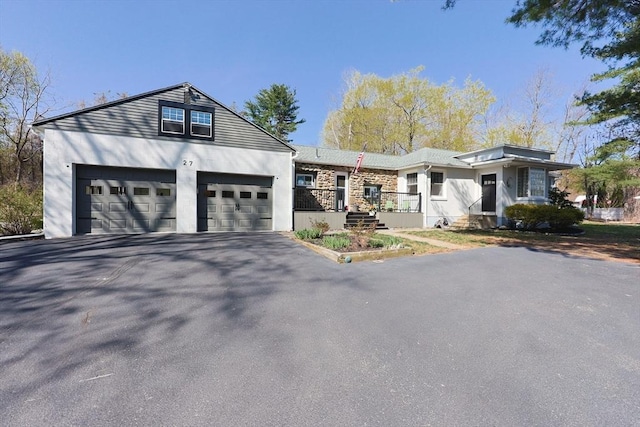 view of front of property with driveway, stone siding, an attached garage, and stucco siding