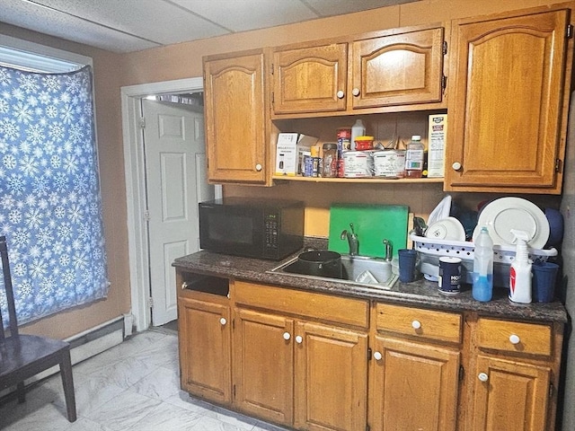 kitchen with black microwave, marble finish floor, brown cabinetry, and a sink