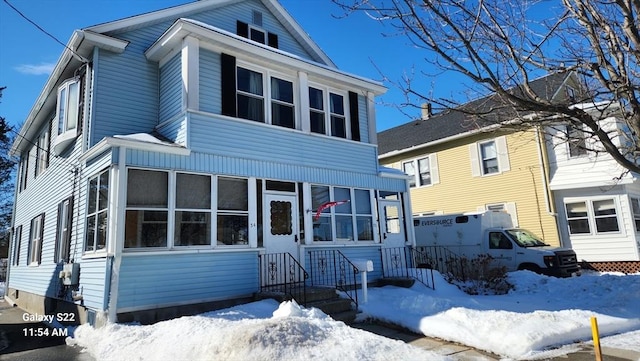 view of front facade with entry steps and a sunroom