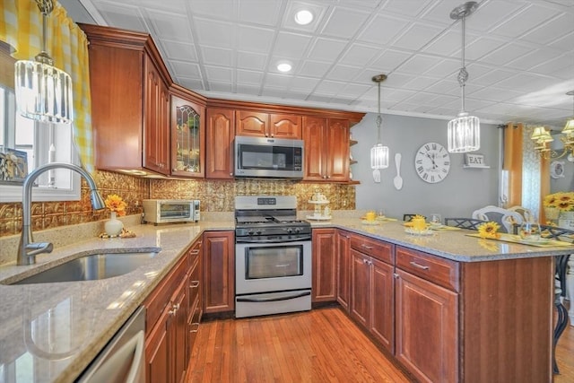 31 Darling St, Acushnet, MA 02743 - kitchen with a peninsula, light wood-type flooring, light stone counters, a sink, and appliances with stainless steel finishes