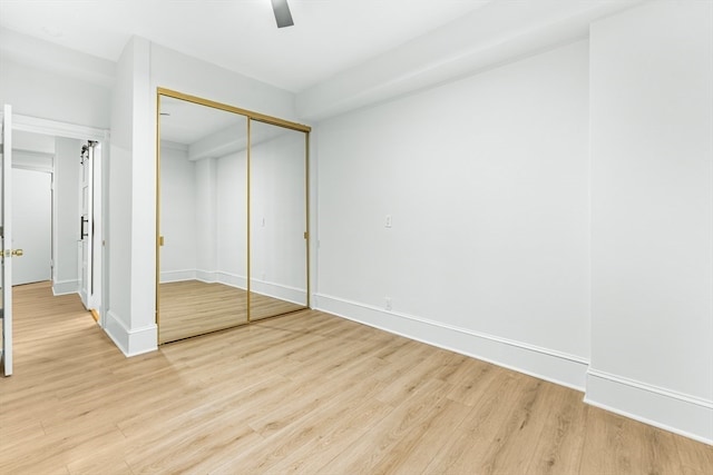 unfurnished bedroom featuring light hardwood / wood-style floors, ceiling fan, and a closet