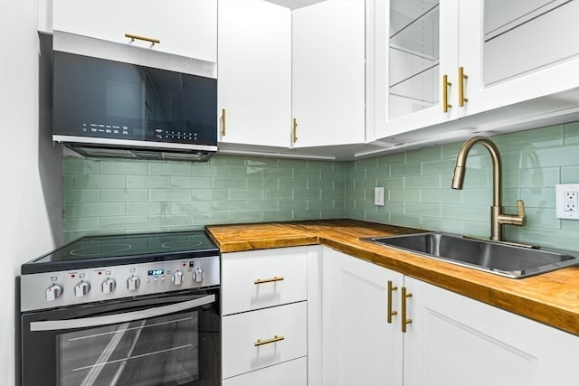 kitchen with stainless steel appliances, wooden counters, white cabinetry, decorative backsplash, and sink