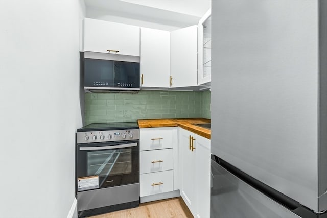 kitchen featuring white cabinets, decorative backsplash, stainless steel appliances, and light hardwood / wood-style flooring