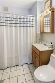 bathroom with toilet, curtained shower, vanity, and tile patterned floors