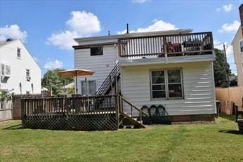 rear view of property with a deck, a yard, and fence