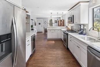 kitchen with stainless steel appliances, a peninsula, a sink, white cabinets, and light countertops