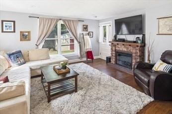 living room with dark wood-style flooring, a fireplace, and baseboards