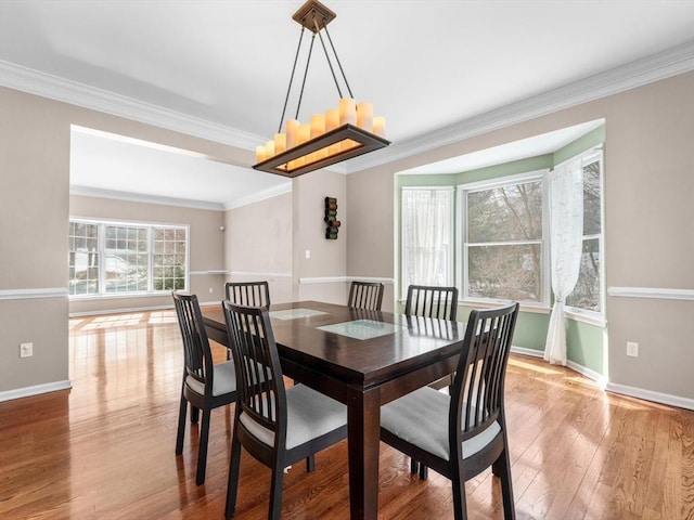 dining space with ornamental molding, wood finished floors, and baseboards