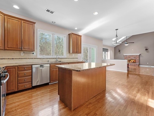 kitchen featuring a fireplace, a kitchen island, visible vents, light wood-style floors, and appliances with stainless steel finishes