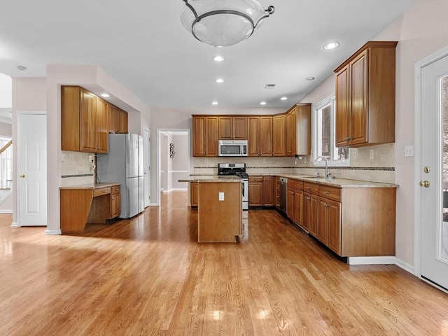 kitchen with stainless steel appliances, a kitchen island, light wood-type flooring, brown cabinets, and tasteful backsplash