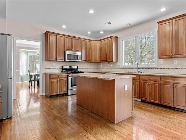 kitchen featuring appliances with stainless steel finishes, light wood-style floors, a healthy amount of sunlight, and a sink