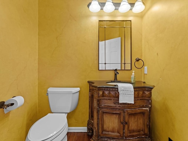 bathroom with baseboards, vanity, toilet, and wood finished floors