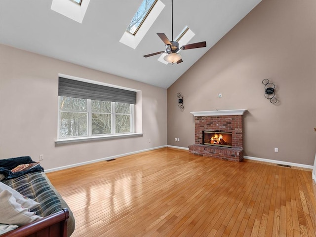 living area with visible vents, a ceiling fan, light wood-type flooring, a fireplace, and high vaulted ceiling