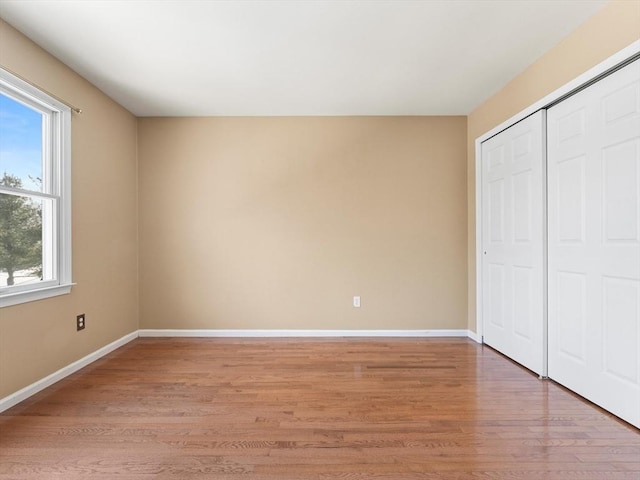 unfurnished bedroom with a closet, baseboards, and light wood finished floors