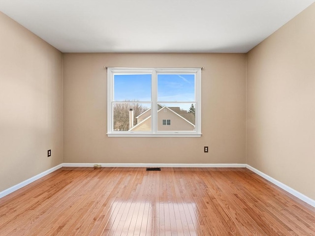 unfurnished room featuring light wood finished floors, visible vents, and baseboards