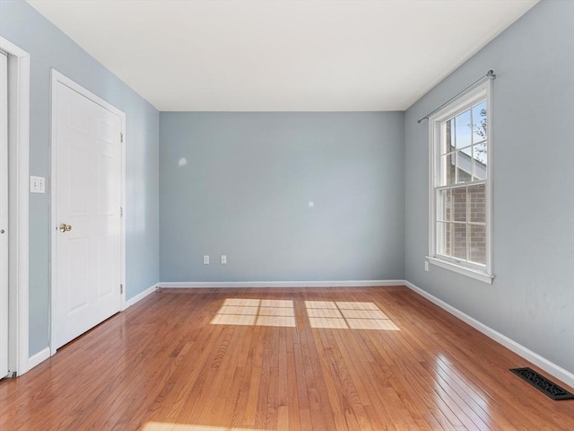 spare room featuring baseboards, visible vents, and light wood-style floors