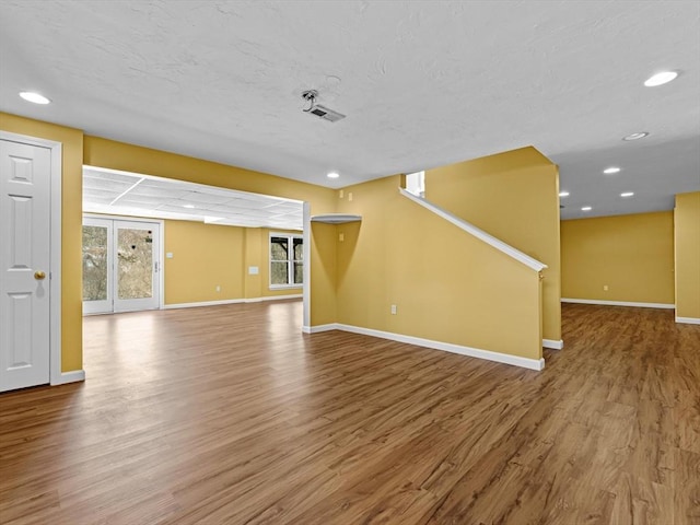 unfurnished living room featuring recessed lighting, visible vents, a textured ceiling, wood finished floors, and baseboards