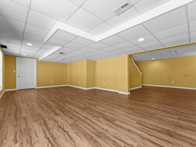 interior space with a drop ceiling, wood finished floors, visible vents, and baseboards