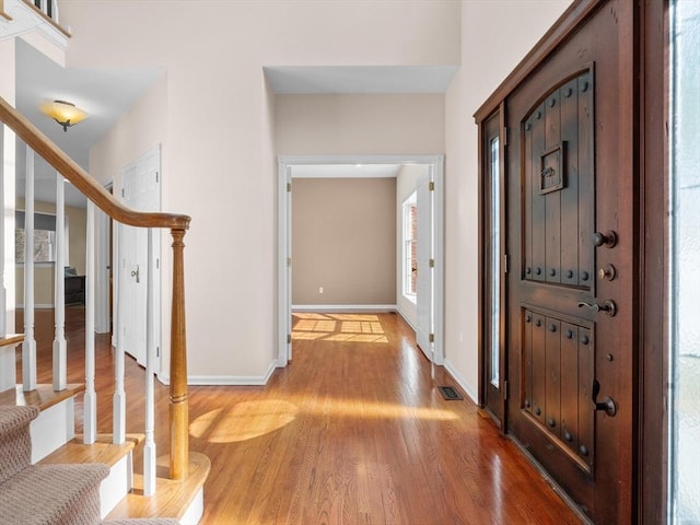 entryway featuring visible vents, light wood-style flooring, baseboards, and stairs