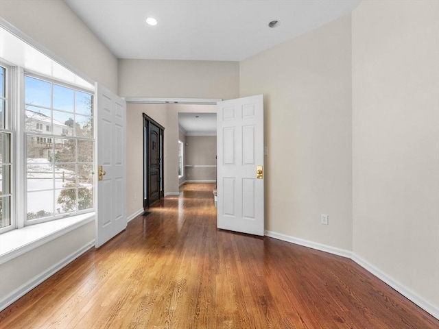 spare room with a barn door, recessed lighting, wood finished floors, and baseboards