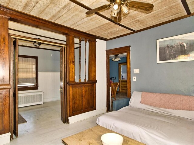 bedroom featuring a wainscoted wall, radiator heating unit, light wood-type flooring, and wood ceiling