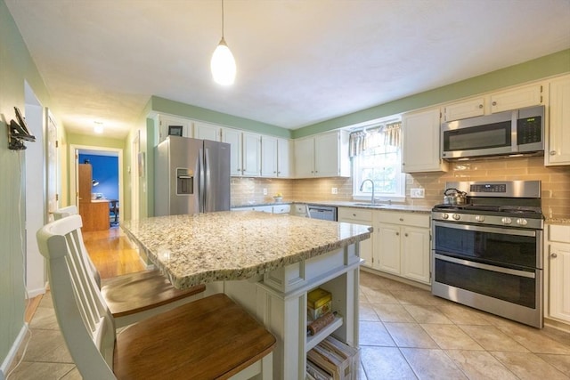 165 Roundtop Rd, Marlborough, MA 01752 - kitchen with stainless steel appliances, a sink, backsplash, a kitchen island, and light stone countertops