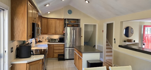 kitchen featuring stainless steel refrigerator, range with electric cooktop, light tile patterned floors, backsplash, and vaulted ceiling