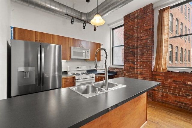 kitchen featuring dark countertops, white appliances, brick wall, and brown cabinets