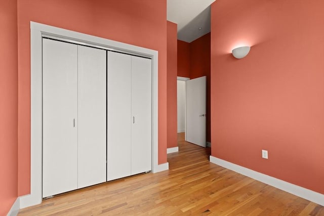 unfurnished bedroom with light wood-style floors, a closet, and baseboards