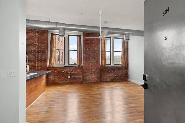 empty room featuring brick wall and wood finished floors