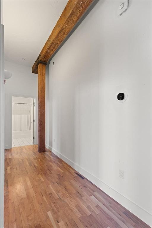 interior space with beam ceiling, baseboards, and wood finished floors