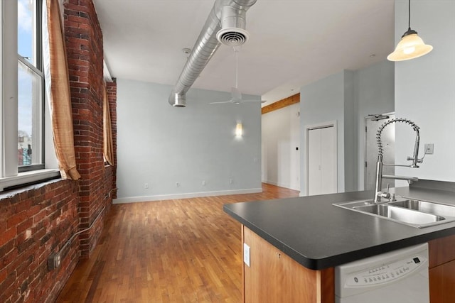 kitchen featuring visible vents, dark countertops, brick wall, white dishwasher, and a sink