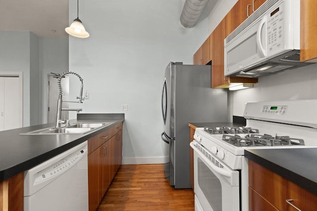 kitchen featuring dark countertops, white appliances, brown cabinets, and a sink