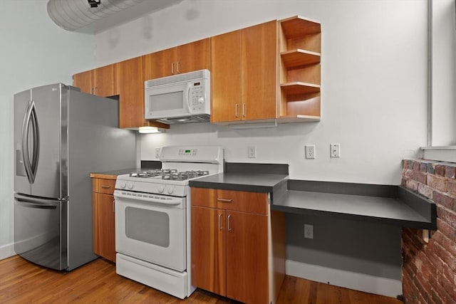 kitchen with white appliances, light wood-style floors, open shelves, brown cabinetry, and dark countertops