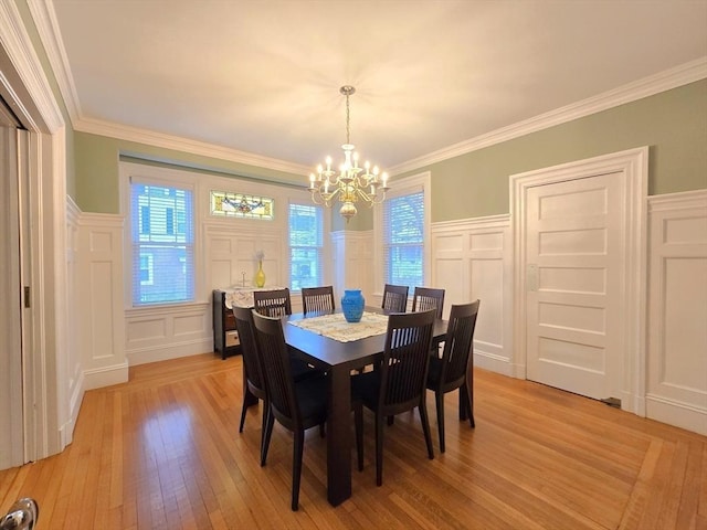 dining room with crown molding, light wood-type flooring, a chandelier, and a decorative wall