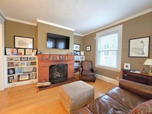 living room featuring ornamental molding, a brick fireplace, baseboards, and wood finished floors