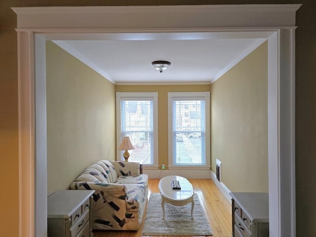 living area with light wood-style floors, crown molding, and baseboards