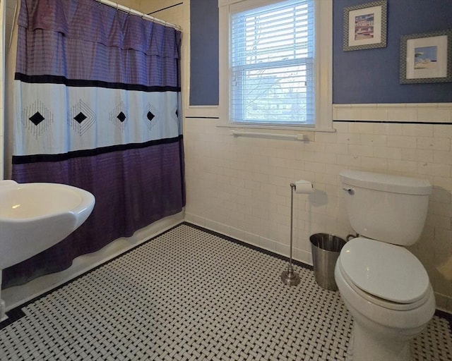 bathroom featuring wainscoting, a shower with shower curtain, toilet, and tile patterned floors