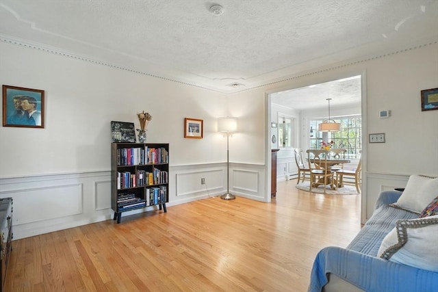 living area featuring light wood-style flooring, a textured ceiling, and a decorative wall