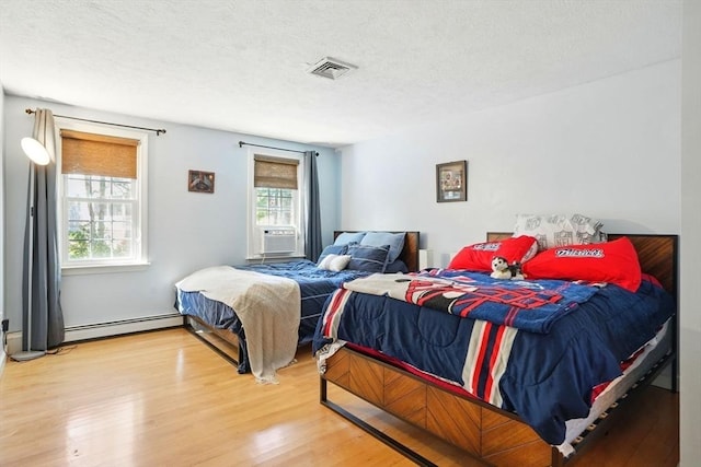 bedroom with a textured ceiling, cooling unit, visible vents, baseboard heating, and wood finished floors