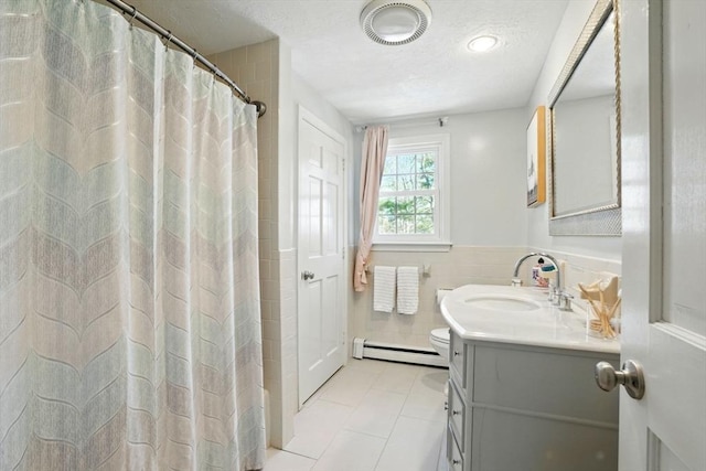 full bathroom with baseboard heating, vanity, tile walls, a wainscoted wall, and visible vents