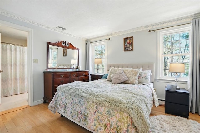 bedroom with visible vents, light wood-style floors, and ornamental molding