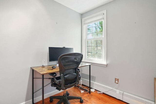 office space featuring a baseboard radiator, baseboards, and wood finished floors