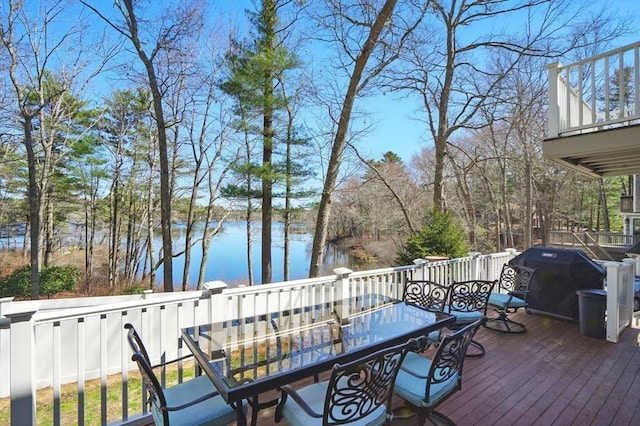 wooden terrace featuring a grill, outdoor dining area, and a water view
