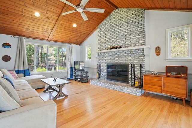 living area featuring beamed ceiling, a ceiling fan, wood finished floors, a brick fireplace, and wood ceiling