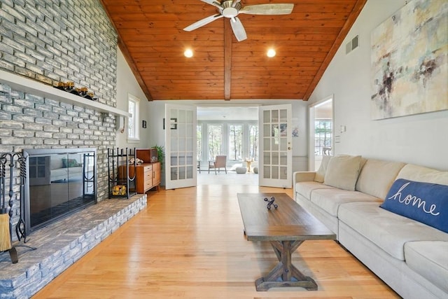 living area with light wood-type flooring, ceiling fan, french doors, a brick fireplace, and visible vents