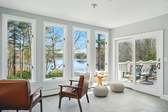 sunroom featuring a baseboard heating unit, a healthy amount of sunlight, tile patterned flooring, and a water view