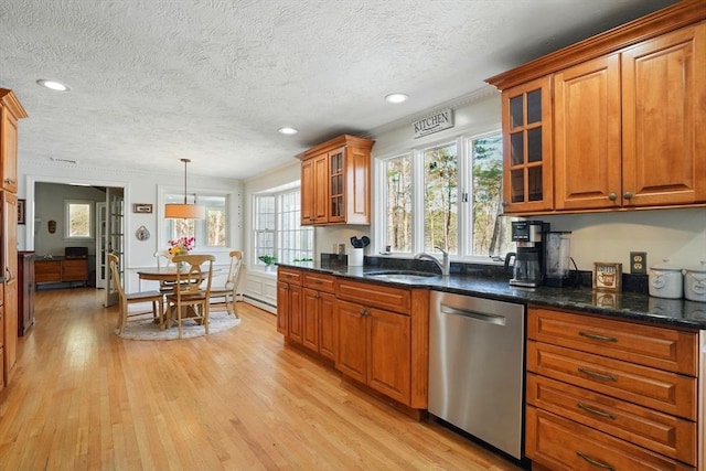 kitchen with brown cabinetry, stainless steel dishwasher, a textured ceiling, and light wood-style flooring